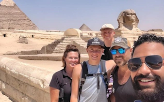 Group of tourists with the Sphinx and pyramids in the background during a Saqqara, Memphis, and Dahshur tour.