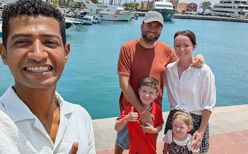 Family with guide at Hurghada marina, boats in background, during private tour.