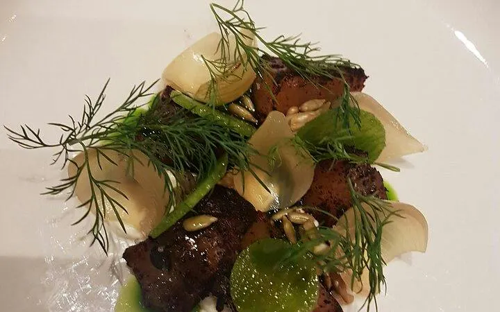 Grilled meat dish with herbs and seeds served at Grand Hotel Oslo during Oslo walking tour.