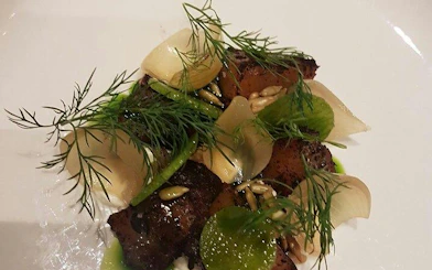 Grilled meat dish with herbs and seeds served at Grand Hotel Oslo during Oslo walking tour.