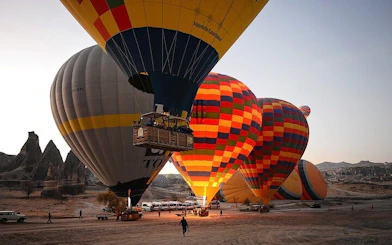 Hot air balloons preparing for sunrise flight over Cappadocia landscape.