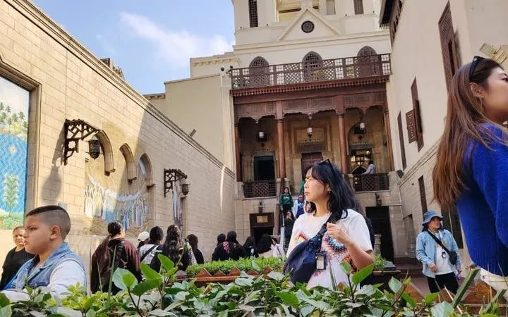 Visitors exploring the historic Coptic Cairo with traditional architecture in the background.