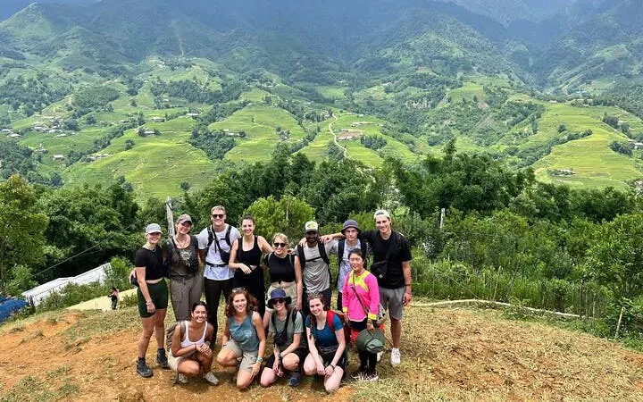 Group of trekkers on Sapa's Y Linh Ho trail with lush green hills in the background.
