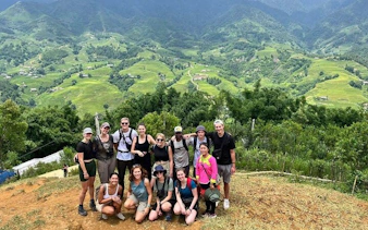 Group of trekkers on Sapa's Y Linh Ho trail with lush green hills in the background.