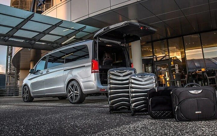 Van with open trunk and luggage at airport terminal for Hurghada hotel transfer service.