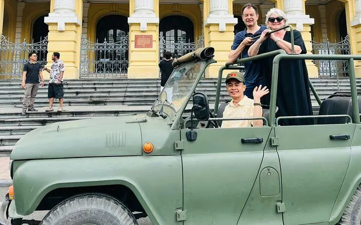 Jeep tour in Hanoi with tourists and driver in front of historic building.