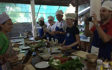 Cooking class participants at Baan Hongnual, Chiang Mai, preparing Thai dishes with fresh ingredients.