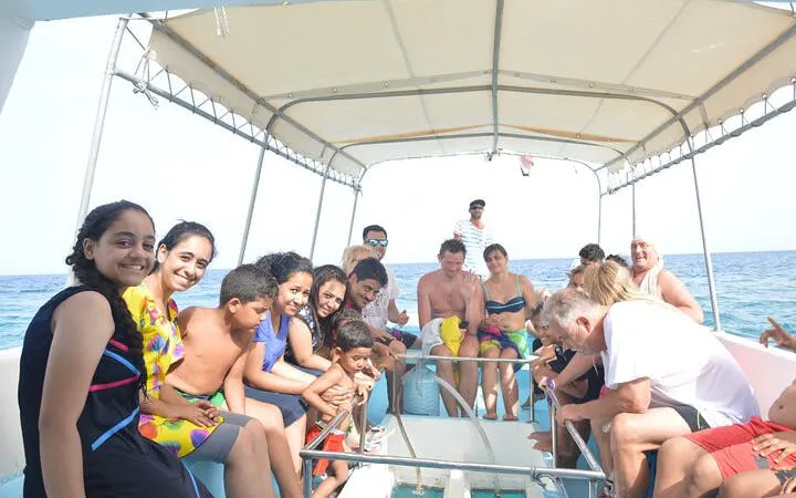 Tourists enjoying a glass-bottom boat trip in Sharm El Sheikh, viewing marine life through the clear sea.