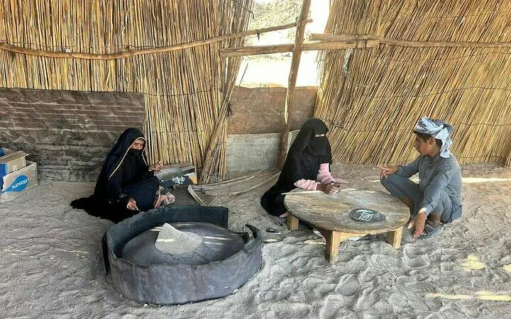 Desert camp with locals sitting around a table, Sharm El Sheikh safari experience.