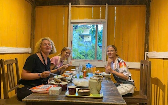 Family enjoying Bun Cha cooking class in a cozy Vietnamese home setting.