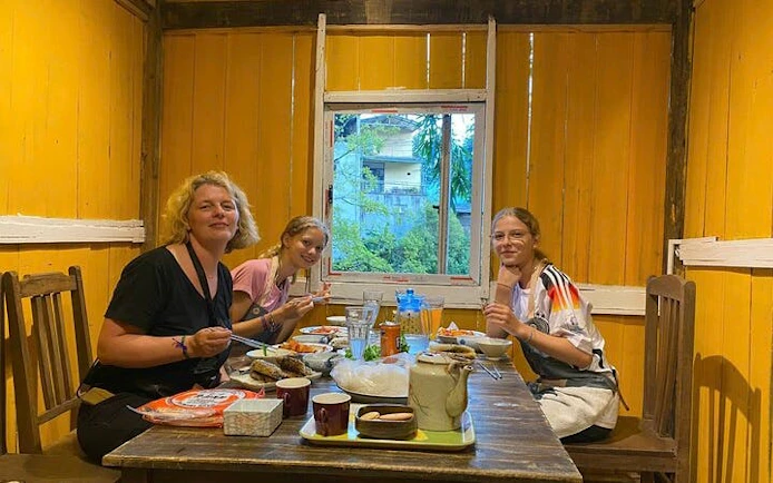 Family enjoying Bun Cha cooking class in a cozy Vietnamese home setting.