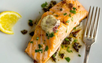 Grilled salmon with herbs and lemon slice on a plate, part of Sapa food tour dinner.