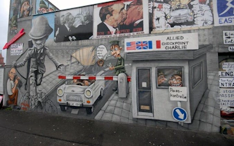 Berlin Wall mural depicting Checkpoint Charlie escape scene on self-guided walking tour.