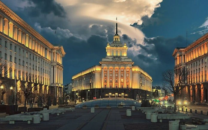 Sofia city center with illuminated government buildings at dusk.