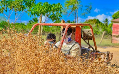 Tourists driving a buggy through muddy terrain in Punta Cana jungle.