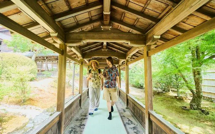 Visitors walking through a wooden corridor at Tenryu-ji Temple, Kyoto, during Arashiyama tour.