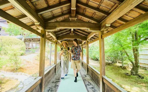 Visitors walking through a wooden corridor at Tenryu-ji Temple, Kyoto, during Arashiyama tour.