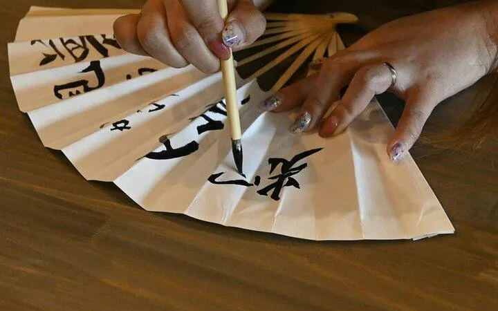 Calligraphy brush writing on a paper fan during Mt. Fuji class, Yamanashi.