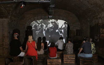 Visitors watching historical film at Time Machine Budapest exhibition.