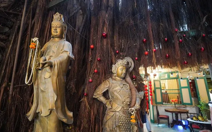 Statues under a banyan tree in Bang Rak, Bangkok, part of a cultural walking tour.