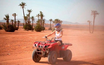 ATV quad bike rider in desert near palm trees, Sharm El Sheikh.