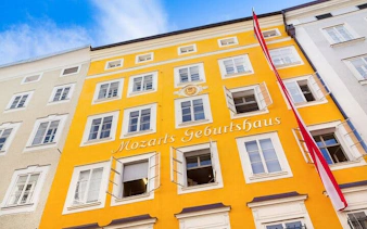 Mozart's birthplace in Salzburg with yellow facade and Austrian flag.