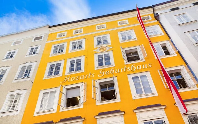 Mozart's birthplace in Salzburg with yellow facade and Austrian flag.
