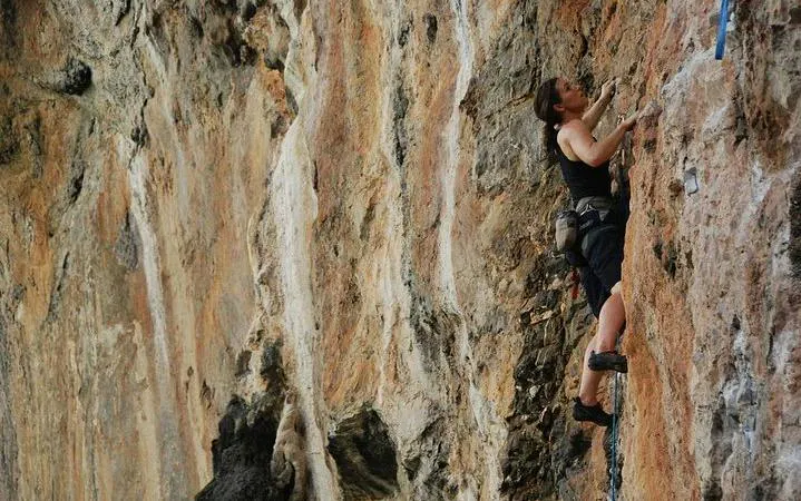Rock climber scaling limestone cliffs at Railay Beach, Krabi.