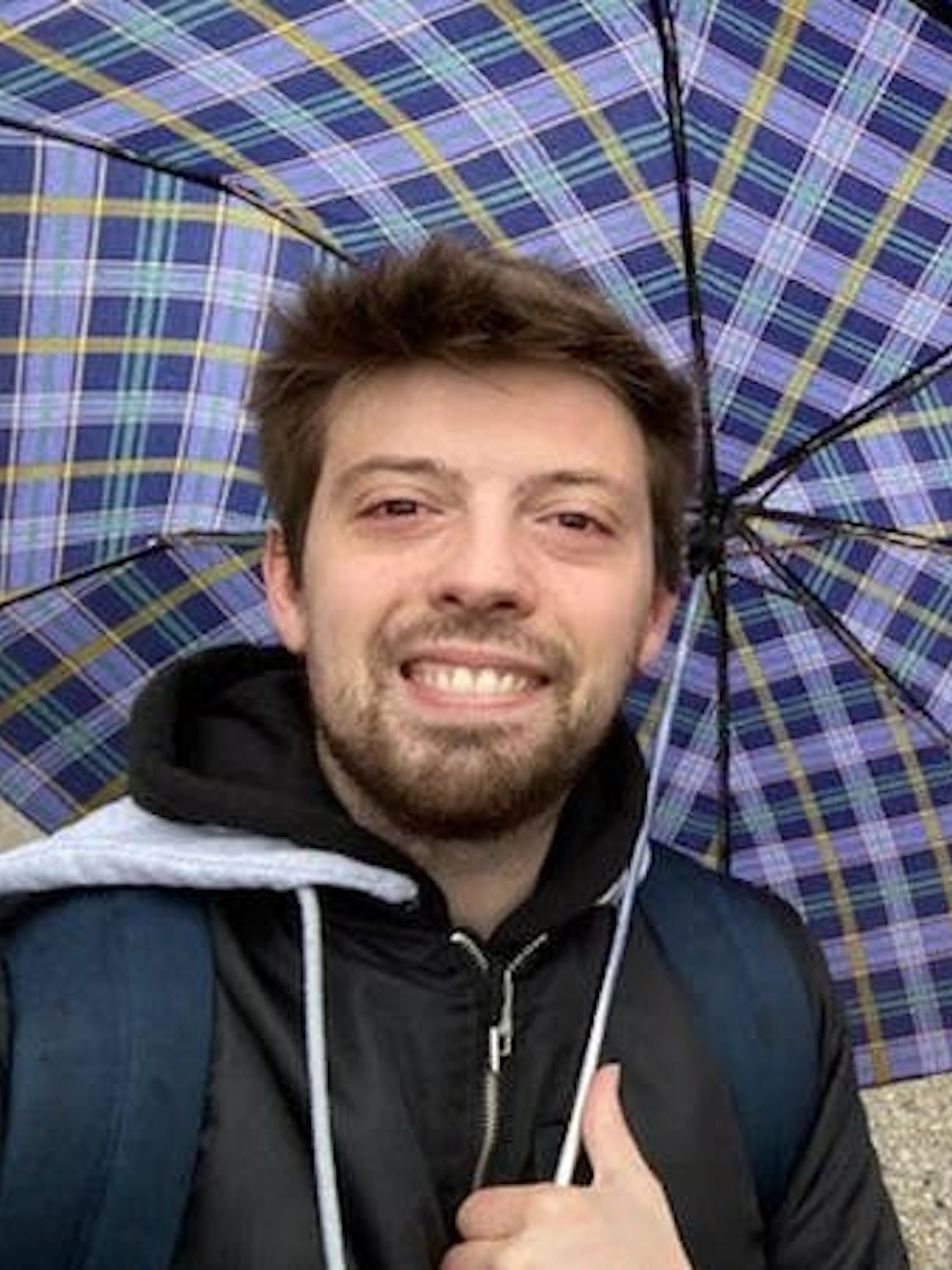 Man with umbrella near Einstein statue in Zurich during self-guided city exploration game.