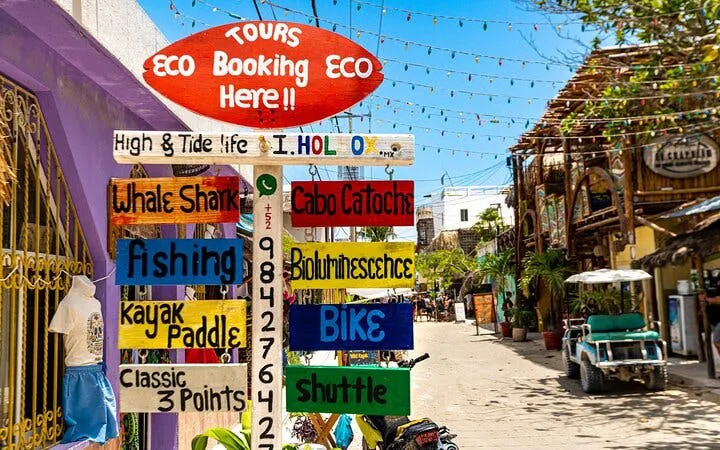 Tour booking sign on Holbox Island street, offering activities like whale shark tours and kayaking.