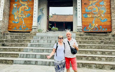 Visitors at Co Loa Citadel entrance, Hanoi, with traditional dragon murals.