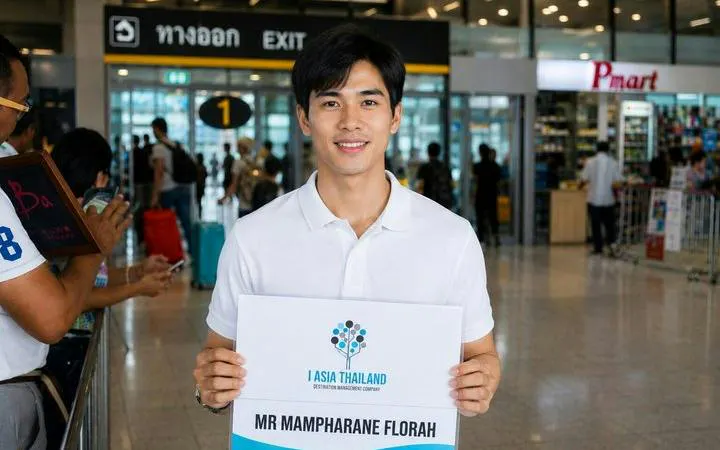 Man holding a sign for private minivan transfer at Bangkok Don Mueang Airport.