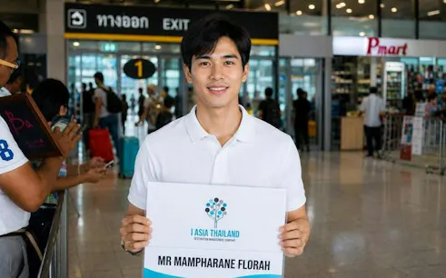 Man holding a sign for private minivan transfer at Bangkok Don Mueang Airport.