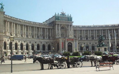 Hofburg Palace in Vienna with horse-drawn carriages in front, part of a self-guided city exploration game.