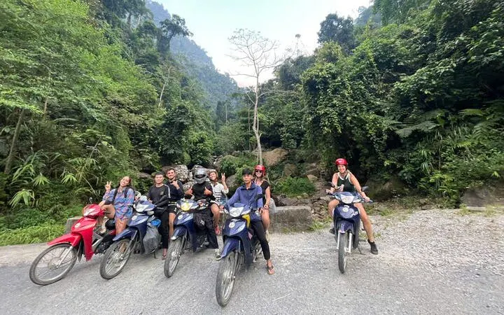 Group on motorbikes in lush Sapa landscape, starting tour to waterfall and Pusamcap Cave.