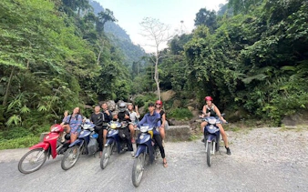 Group on motorbikes in lush Sapa landscape, starting tour to waterfall and Pusamcap Cave.