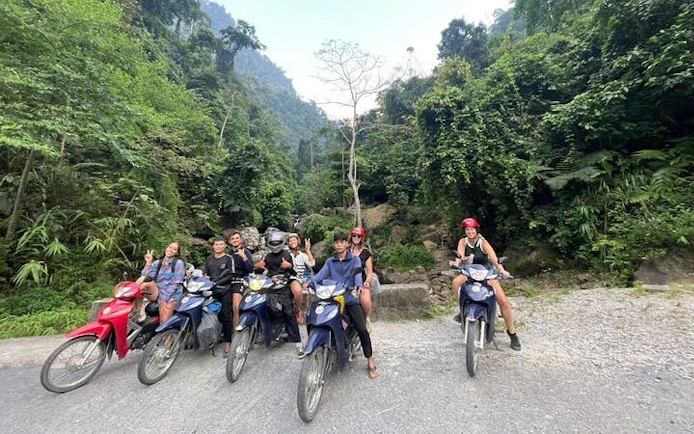 Group on motorbikes in lush Sapa landscape, starting tour to waterfall and Pusamcap Cave.