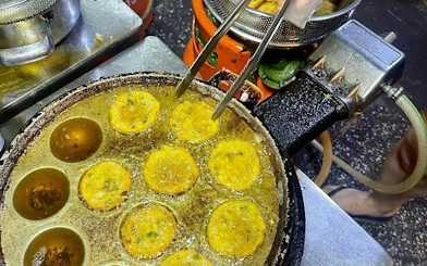 Street food pancakes cooking in a pan during a Ho Chi Minh City motorbike food tour.