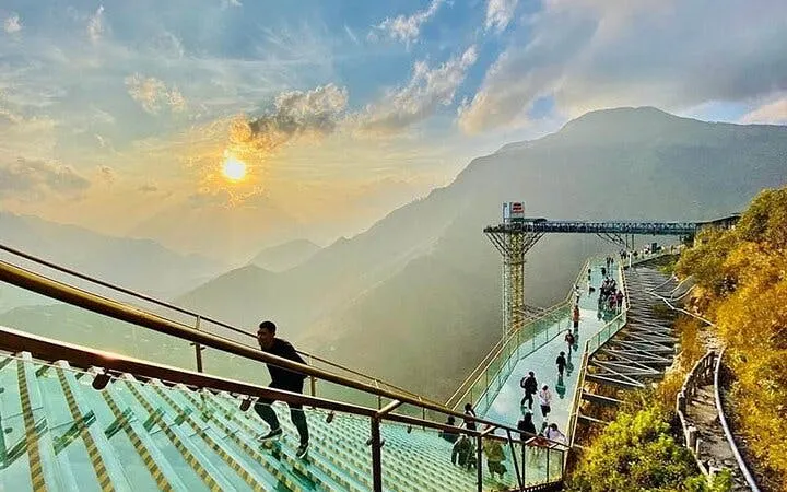Sa Pa Glass Bridge with tourists enjoying mountain views at sunset.