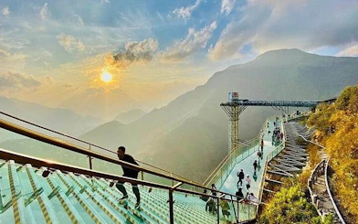 Sa Pa Glass Bridge with tourists enjoying mountain views at sunset.
