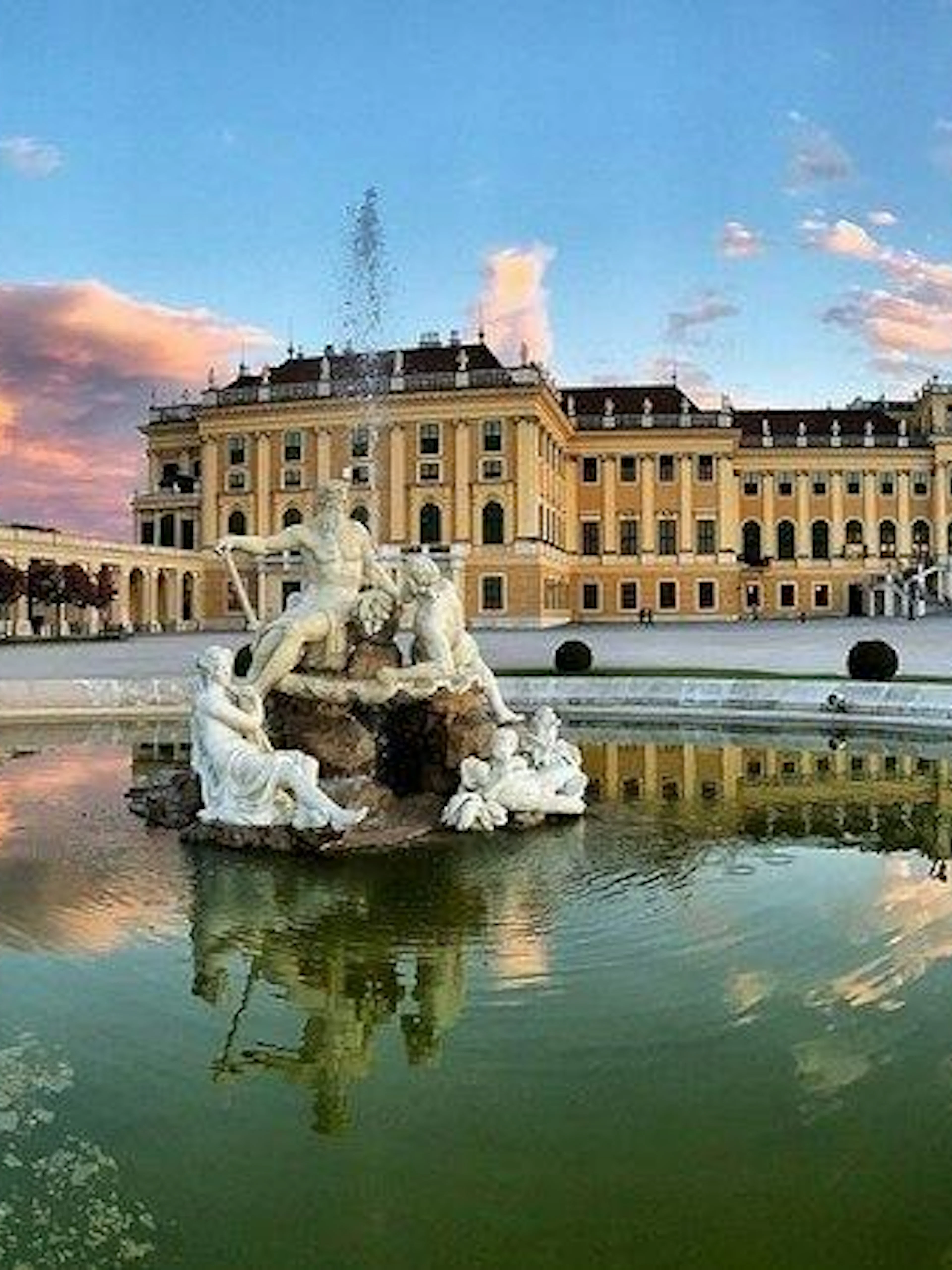 Schönbrunn Palace with Neptune Fountain in Vienna at sunset.