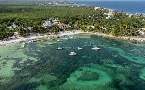 Aerial view of Akumal Bay with boats and snorkelers in turquoise water, Mexico.
