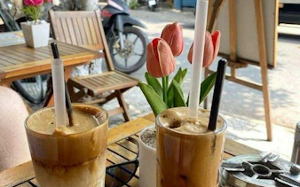 Hanoi street cafe table with iced coffee drinks and tulips, part of E-Scooter City Tour.