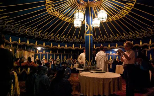 Folklore show inside Moroccan tent with guests dining, Marrakesh.