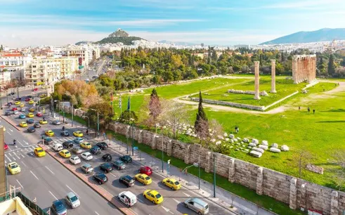 Ancient Temple of Olympian Zeus in Athens with cityscape and Mount Lycabettus in the background.