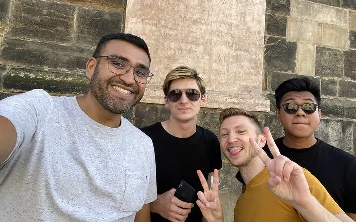 Group of friends posing in front of a historic stone wall in Prague during a self-guided city exploration game.