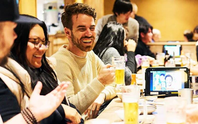 Group enjoying drinks at a lively bar in Shinjuku, Tokyo during a night walking tour.