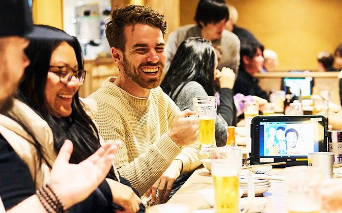 Group enjoying drinks at a lively bar in Shinjuku, Tokyo during a night walking tour.