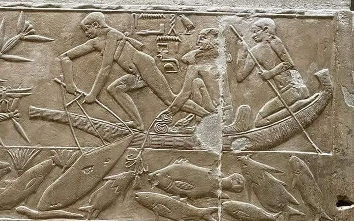 Ancient Egyptian fishermen in a boat carving, Model Village Egypt tour.