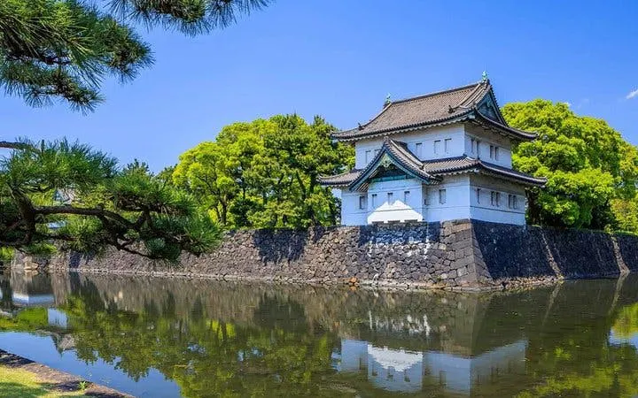 Tokyo Imperial Palace building with surrounding moat and lush greenery.